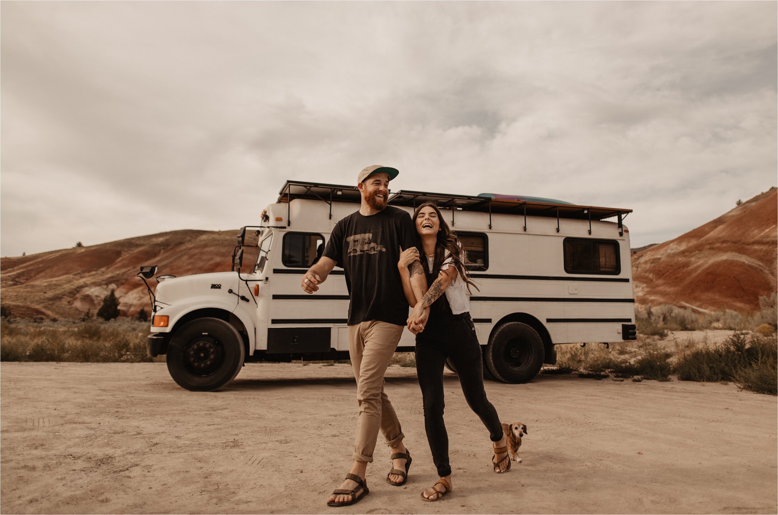 A bus with in the background. A happy couple standing in front of the bus
